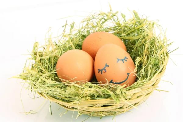 Group of brown hen's eggs with a sleeping face in the nest isola — Stock Photo, Image