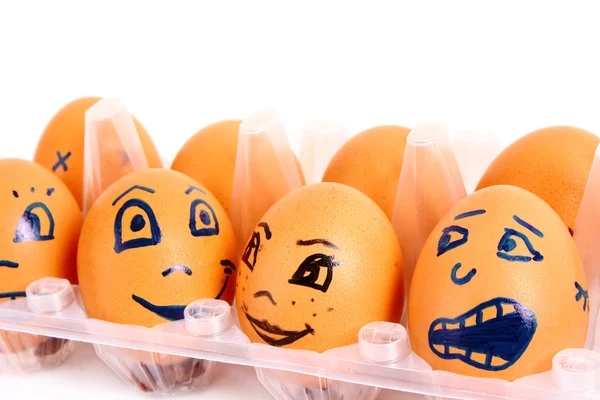 Группа коричневых куриных яиц с разными лицами в коробке — стоковое фото
