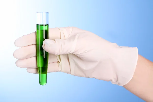 Reagenzglas mit Grün in der Hand über blauem Hintergrund — Stockfoto