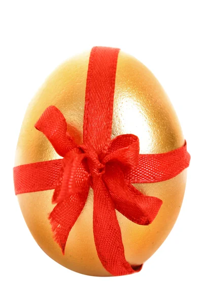 Jeden złoty kurze jajko z czerwoną wstążką na białym tle — Zdjęcie stockowe
