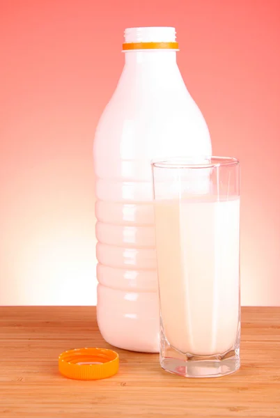 Vaso de leche y botella sobre fondo rojo — Foto de Stock