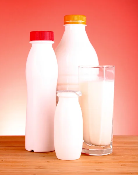 Стакан молока и бутылка на красном фоне — стоковое фото