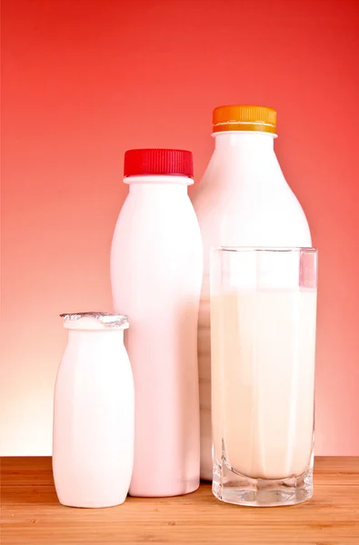 Algumas garrafas brancas com produtos lácteos e um copo de leite em um w — Fotografia de Stock