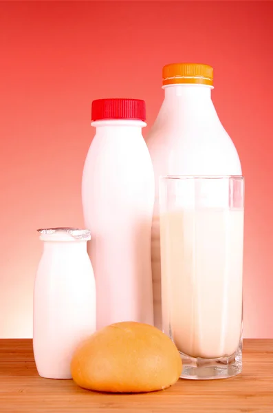 Botella de leche, pan y vidrio sobre fondo rojo — Foto de Stock