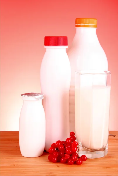 Glas mjölk och flaska på röd bakgrund — Stockfoto