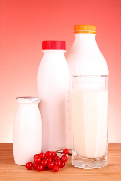Vidro de leite e garrafa no fundo vermelho — Fotografia de Stock