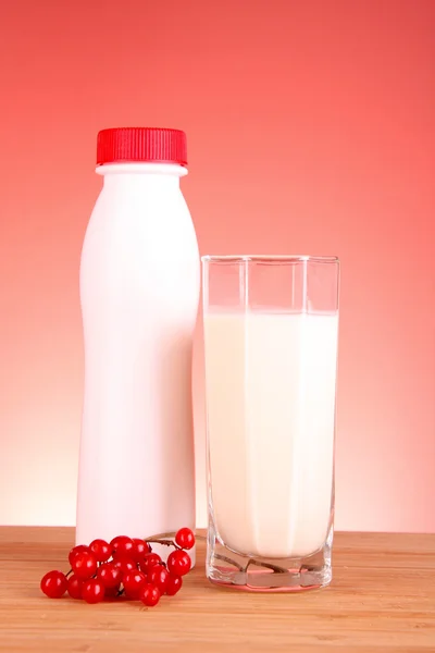 Glas melk en fles op rode achtergrond — Stockfoto