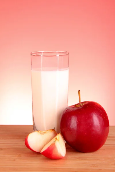Apple och mjölk på röd bakgrund — Stockfoto
