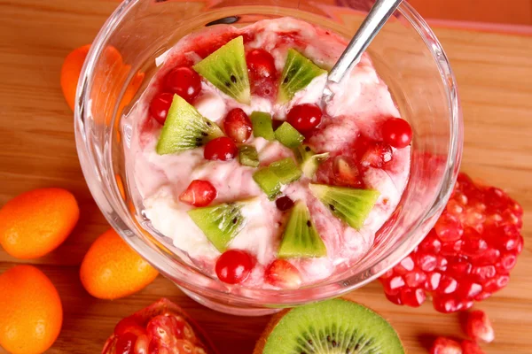 Un po 'di coctail con frutta in vetro con cucchiaio su fondo rosso — Foto Stock