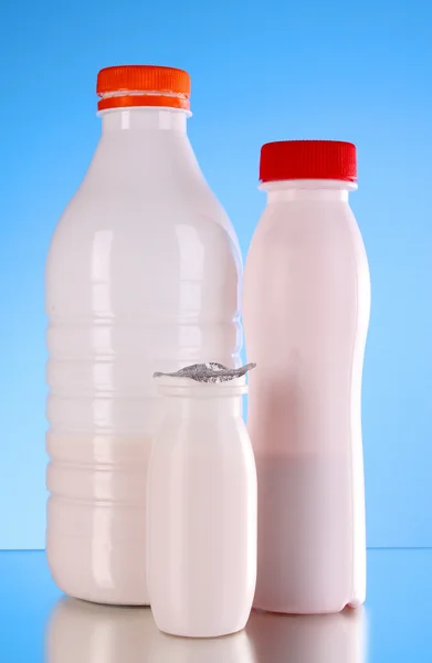 Пляшки молока на синьому фоні — стокове фото