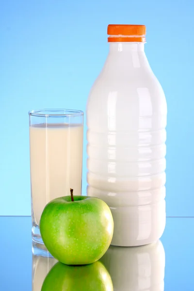 Garrafa de leite e maçã no fundo azul — Fotografia de Stock