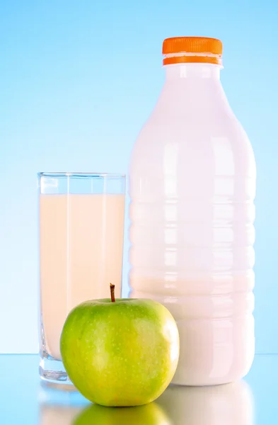 Bottiglia di latte e mela su sfondo blu — Foto Stock