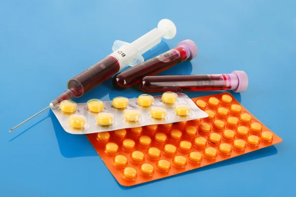 Medizinische Reagenzgläser mit Blut und Medikamenten auf blau — Stockfoto