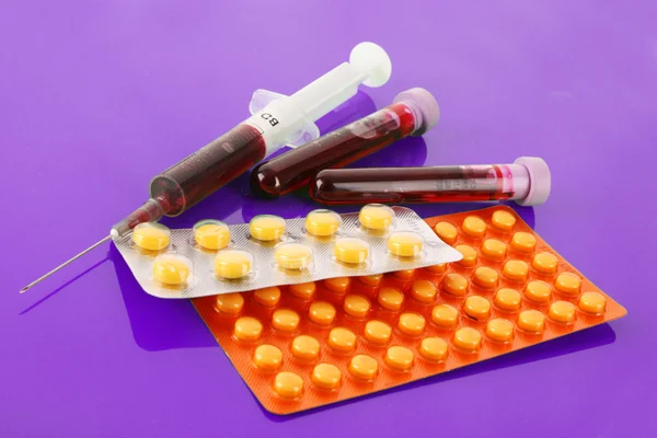 Medical test tubes with blood and medicines on puple — Stock Photo, Image