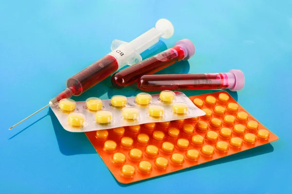 Medische test buizen met bloed en medicijnen op blauw — Stockfoto