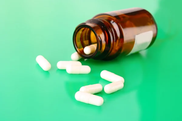 Пляшка таблеток з білими таблетками на зеленому — стокове фото