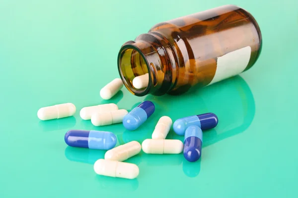 Garrafa pílula com pílulas brancas em azul — Fotografia de Stock