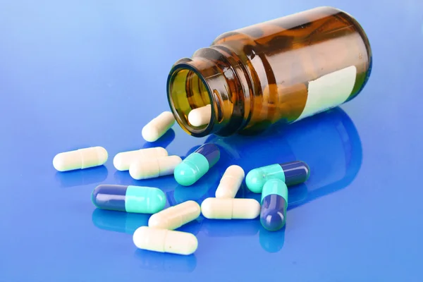 Piller flaska med färgade piller på blå — Stockfoto