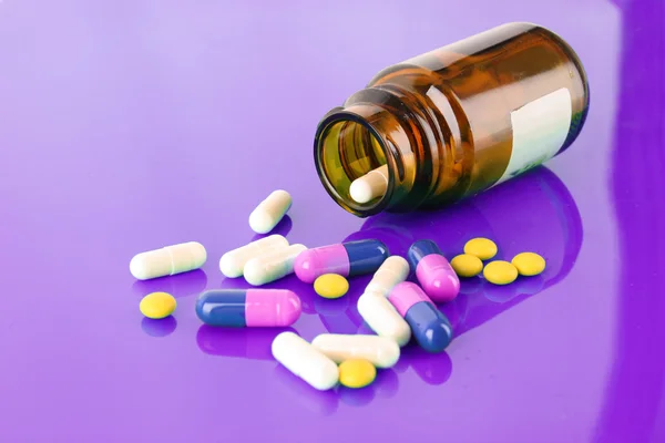 Piller flaska med färgade piller på puple — Stockfoto