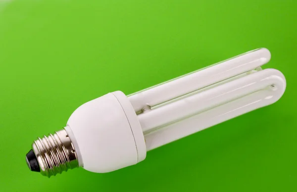 Энергосберегающая лампочка на зеленом — стоковое фото