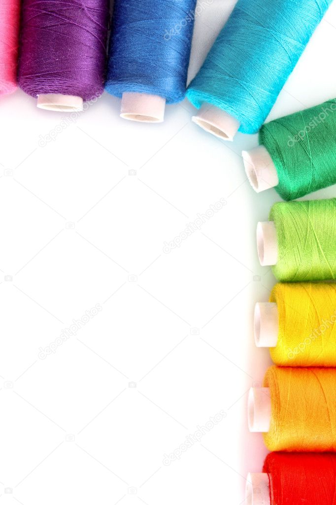 Pile of coloured bobbins of lurex thread isolated on white