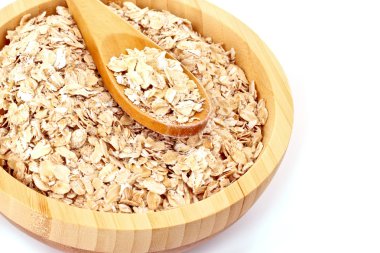 Uncoocked rolled oats in wooden plate isolated on white clipart