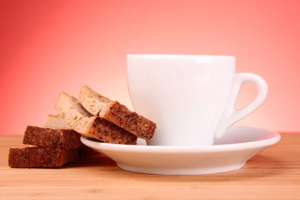 Xícara de café e rusk no fundo vermelho — Fotografia de Stock