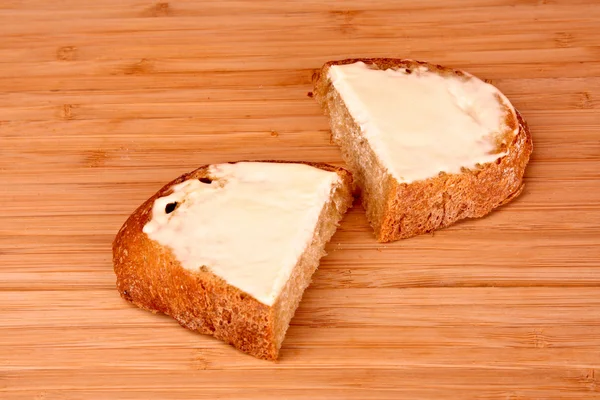 Rebanada de pan con mantequilla en un soporte de madera — Foto de Stock