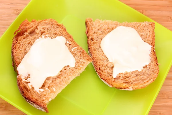 Pão com manteiga em prato verde — Fotografia de Stock