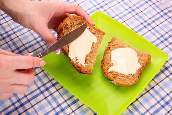 Manos de mujer untar el pan con mantequilla sobre fondo de mesa —  Fotos de Stock