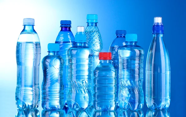 Grupo garrafas de plástico de água no fundo azul — Fotografia de Stock