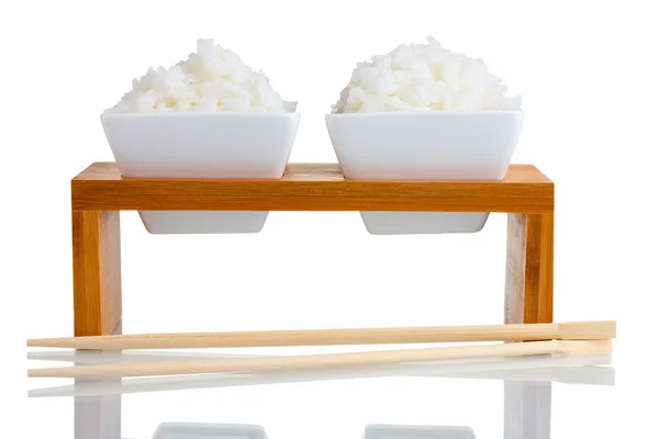 Dwie miski na drewniany stojak z gotowanego ryżu i pałeczki na białym tle — Zdjęcie stockowe