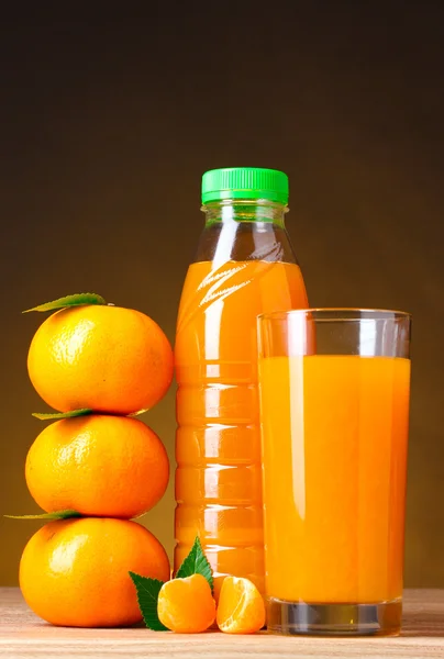 Mandarinas, vaso de jugo y botella sobre mesa de madera sobre respaldo marrón —  Fotos de Stock