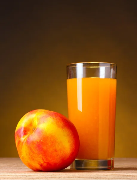 油桃和果汁玻璃棕色背景上的木桌上 — 图库照片