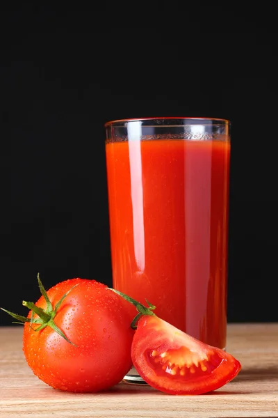 Tomatsaft i glas och tomat på träbord på brun bakgrunds — Stockfoto