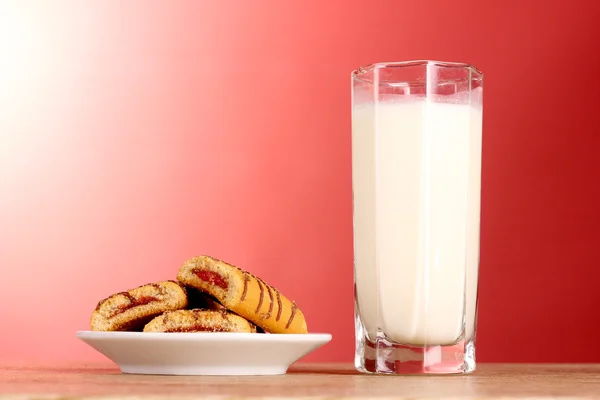 Cookies with milk on red background — Stock Photo, Image