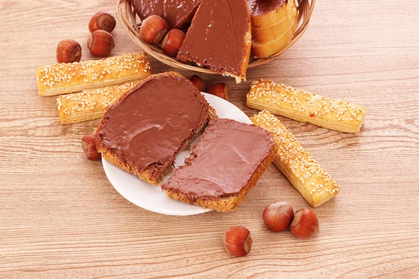 Pâine, prăjituri și nuci cu ciocolată pe masă de lemn — Fotografie, imagine de stoc