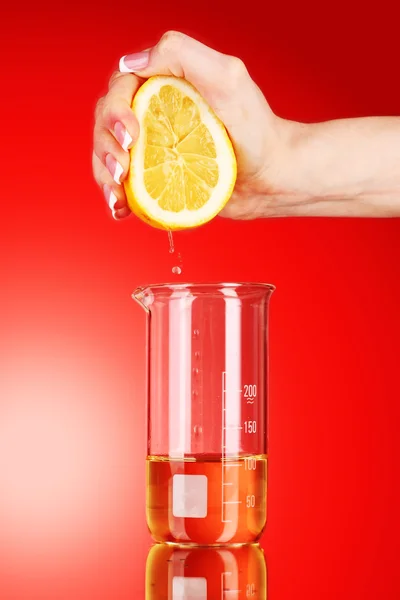 stock image Someone squeeze lemon on a red background