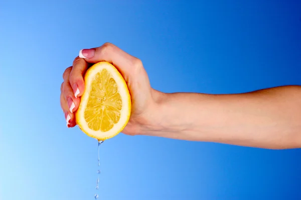 Alguém espremer limão em um fundo azul — Fotografia de Stock