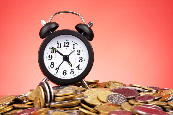 Relógio despertador e moedas em fundo vermelho — Fotografia de Stock
