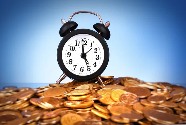 Alarm clock with golden coins on blue background — Stock Photo, Image