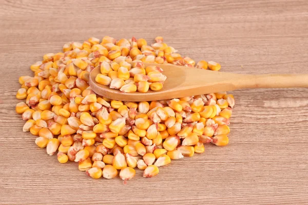 Corn and spoon on brown — Stock Photo, Image