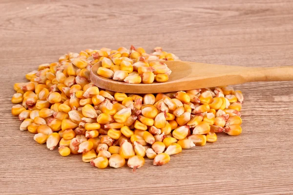 Corn and spoon on brown — Stock Photo, Image