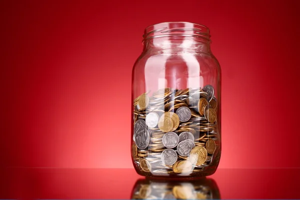 Coins in money jar on red background. Ukrainian coins — Stock Photo, Image