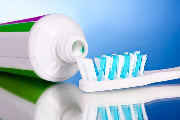 Зубна паста і пензлик на синьому фоні — стокове фото