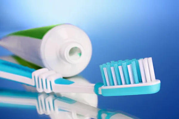 Pasta de dientes y cepillo sobre fondo azul — Foto de Stock