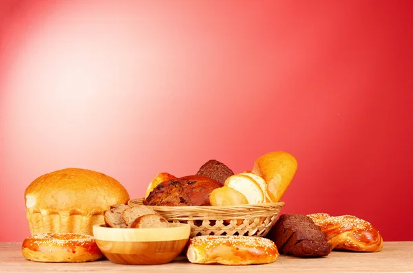 Gebackenes Brotsortiment auf rotem Hintergrund — Stockfoto