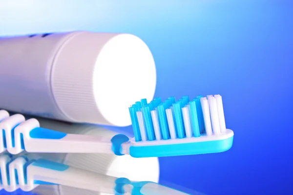 Dentifricio e spazzolino da denti su sfondo blu — Foto Stock