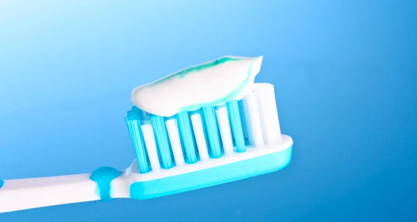 Cepillo de dientes con pasta de dientes sobre fondo azul — Foto de Stock