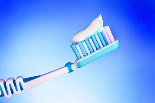 Sikat gigi dengan pasta gigi pada latar belakang biru — Stok Foto